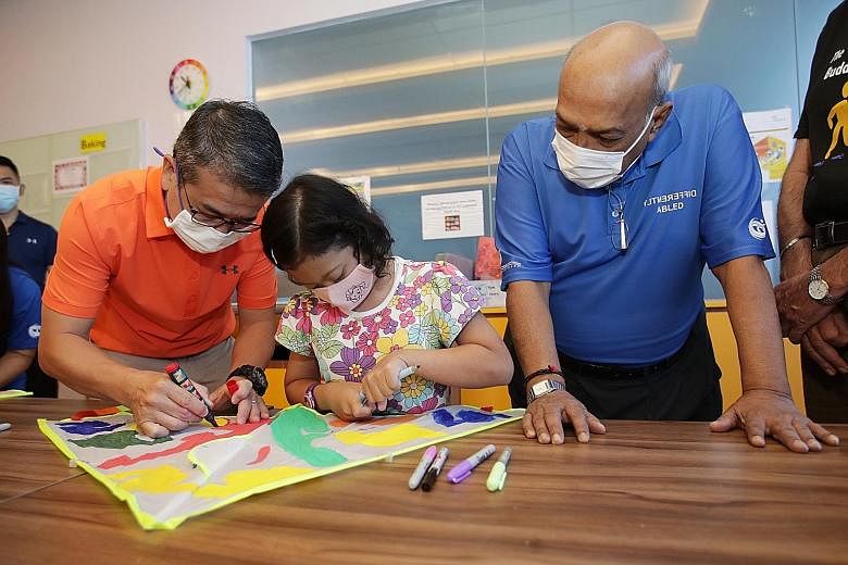 Minister for Culture, Community and Youth Edwin Tong drawing on a kite with Down Syndrome Association (Singapore) beneficiary Nur Alyssa Azli, 11, at the association's World Down Syndrome Day event at the DSA Centre at Junction 8 Office Tower yesterd
