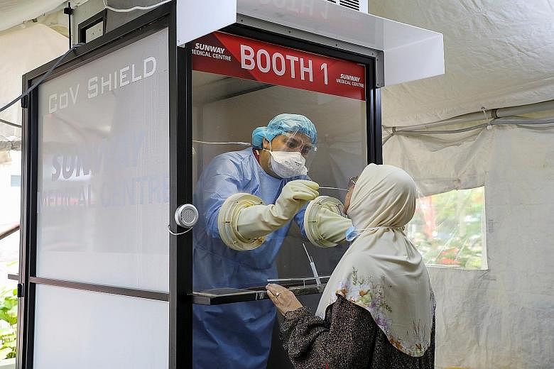 A medical worker collecting a swab sample from a woman to be tested for Covid-19 in Subang Jaya, Malaysia, this month. Health experts have urged caution over allowing interstate travel as the pandemic is still a threat.