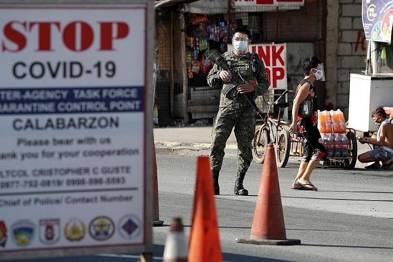 Security personnel manning a checkpoint at the border between Metro Manila and Cavite province in the Philippines yesterday. Leisure travel out of Metro Manila and four nearby provinces, including Cavite, has been banned in a bid to curb an outbreak 
