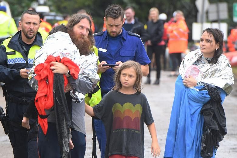 Above: A child being evacuated in Upper Colo, north-western Sydney, yesterday. Australia's emergency services have carried out about 850 rescues during the floods so far. Below: A family that was rescued after their boat capsized as they were being e