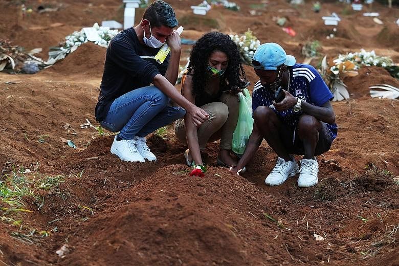 Relatives of a 65-year-old coronavirus victim paying respects at her grave at a cemetery in Sao Paulo this week. Brazil's new record number of daily Covid-19 deaths on Tuesday underlines the scale of the country's outbreak, which is spiralling out of
