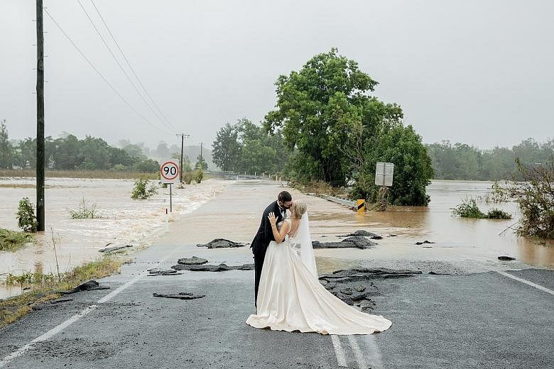 Newlyweds Wayne and Kate Bell in front of the flooded bridge in New South Wales that blocked Mrs Bell's way to her wedding venue on Saturday. She eventually arrived at the venue in a helicopter sent by a local TV station.