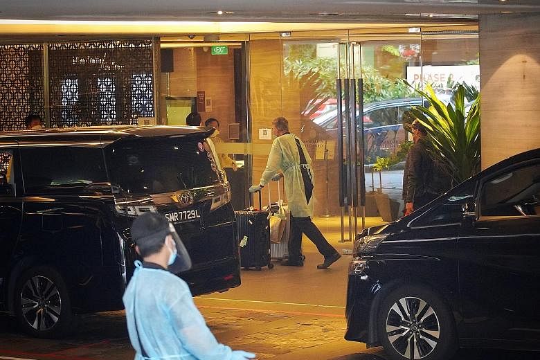 Staff in personal protective equipment moving luggage as guests leave the Mandarin Orchard Singapore hotel on Dec 20 last year. All guests, including local guests on staycation at the hotel's other wing, were moved out as the authorities investigated