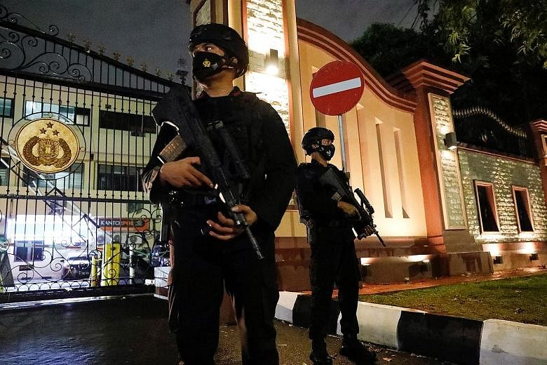 Armed police officers stand guard at the gate of national police headquarters in Jakarta following an attack on Wednesday. The 25-year-old attacker, a female college dropout, was active on social media, and an intelligence and terrorism expert said s