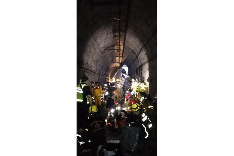 Rescuers working in a tunnel in Hualien County in eastern Taiwan where a Taroko Express train derailed yesterday after hitting a truck that had slid onto the train track at the mouth of the tunnel.