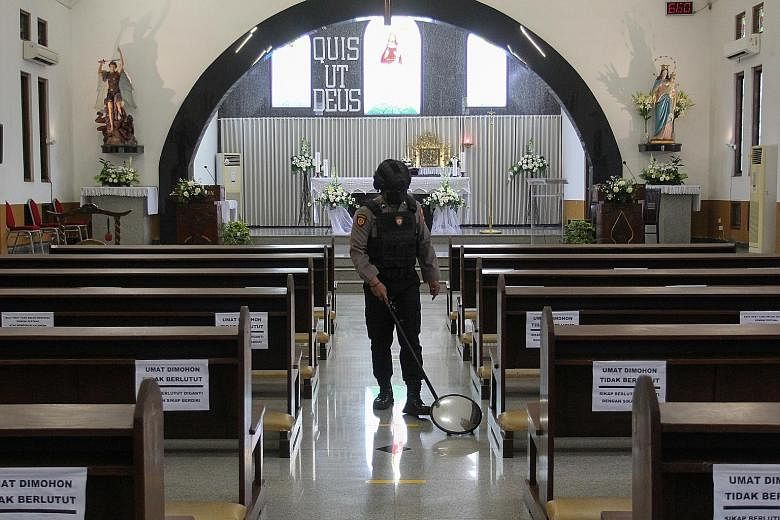 A police officer inspecting church pews in Surabaya last Thursday. Security forces were on heightened alert following the terror attack in Makassar on Palm Sunday. PHOTO: REUTERS