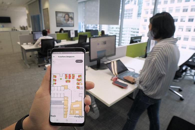 A smartphone app being used by a Vodafone staff member to check and book slots for workstations at the firm's office in Marina Bay. With fewer workers in the office, companies may choose to downsize and save on rent. Some are also redesigning the wor