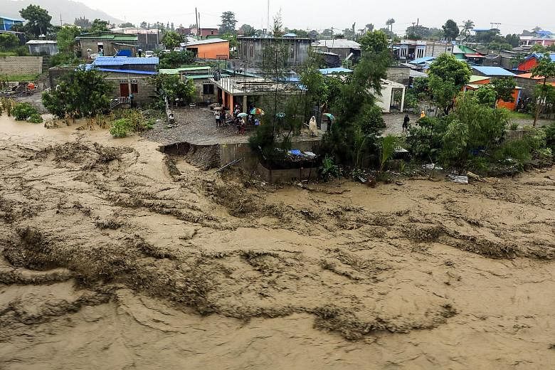 People keeping to higher ground as a river swelled due to flooding in Dili, Timor-Leste, on Sunday. At least 27 people in the country were killed by landslides, flash floods, as well as a falling tree, while 7,000 were displaced.