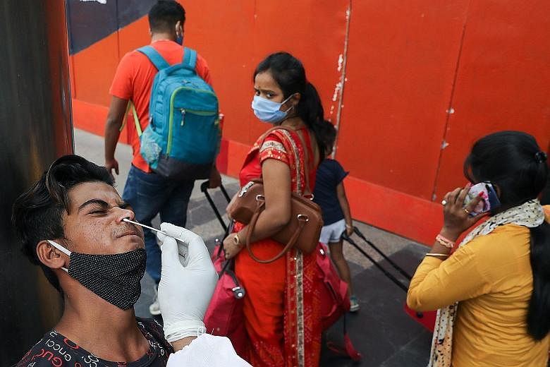 A man being swabbed by a healthcare worker at a railway station in New Delhi yesterday as the country battles a fresh wave of infections, recording almost 116,000 new cases in 24 hours.