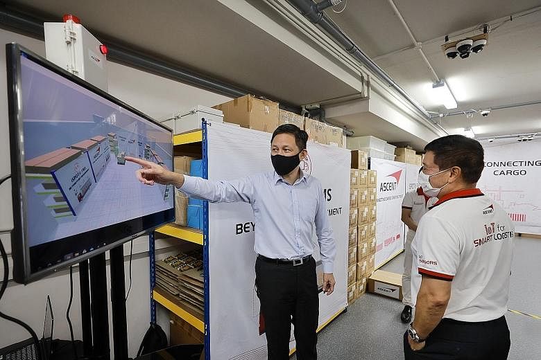 Trade and Industry Minister Chan Chun Sing (left) looking at Ascent Solutions' warehouse cargo tracking system with its chief executive Lim Chee Kean at the company's office in Pasir Panjang Road yesterday. The solution will allow the company's clien