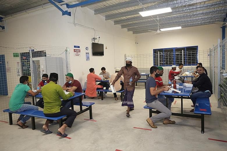 Migrant workers having their pre-dawn meals at the Quick Build Dormitory in Choa Chu Kang Grove yesterday. More than 800 meals were handed out to Muslim workers at the dorm by Senior Minister of State for Manpower and Defence Zaqy Mohamad and volunte