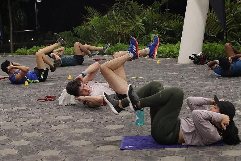 Lieutenant (NS) William Werry working out with his wife Tess Tseng during an NS Fitness Improvement Training (FIT) session at Jurong Lake Gardens yesterday. NS FIT, which replaces the remedial training and IPPT preparatory training schemes, aims to h