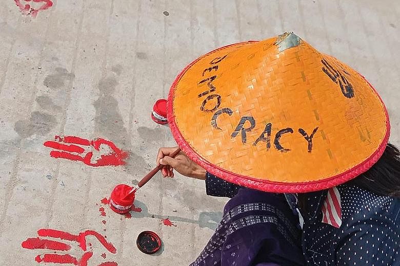 This photo, posted on Facebook and shared by an anonymous source yesterday, shows a protester painting the three-finger salute symbol on the ground with red paint as part of a "bloody paint strike" protest against the military coup in Shwebo, Myanmar