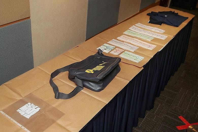 The items seized by the police in Monday's case. Aetos officer Mahadi Muhamad Mukhtar is said to have robbed OT Credit while armed with a revolver, and allegedly took $24,000. He was arrested within five hours on the same day.