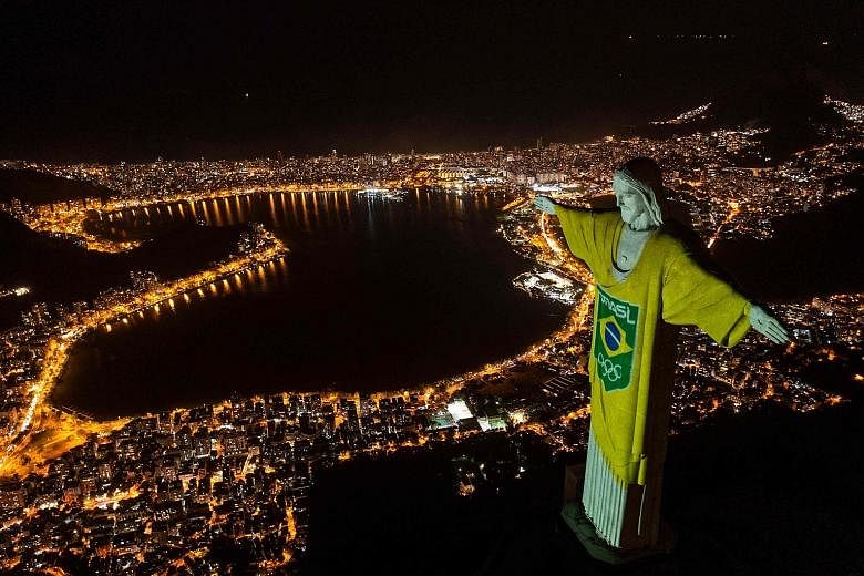 Above: The statue of Christ the Redeemer in Rio de Janeiro is lit with the Brazilian flag colours and Olympic rings to mark 100 days until Tokyo 2020 on Wednesday. Left: At the Olympics, Russian athletes will be wearing uniforms in white, blue and re