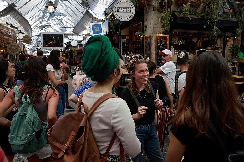 People at a market in Jerusalem yesterday after the Israeli authorities announced that face masks for Covid-19 prevention were no longer required outdoors. With over half the population fully vaccinated in one of the world's fastest anti-coronavirus 
