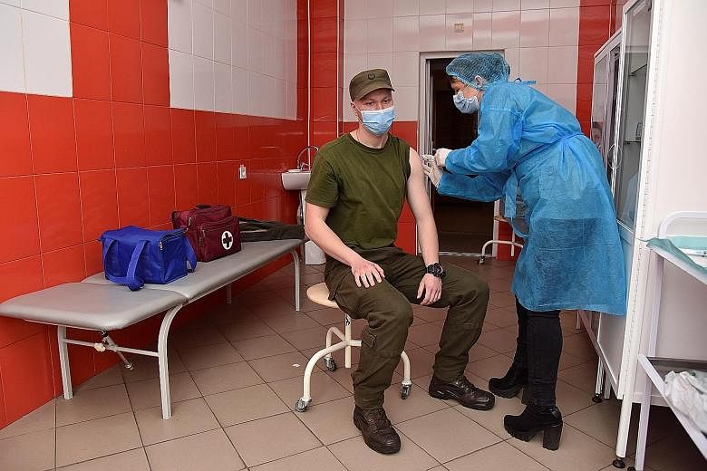 A Ukrainian National Guard soldier receiving an AstraZeneca shot in Lviv last Wednesday. The health situation in Ukraine is becoming more urgent: Daily new cases hit a record of more than 20,000 this month.