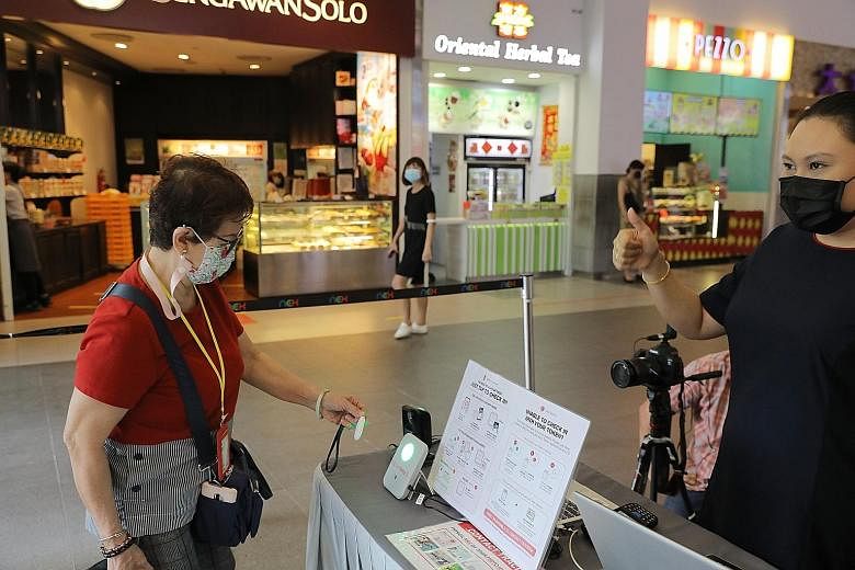 A visitor to Nex mall (above) using her TraceTogether token to check in via the SafeEntry Gateway system last month - the Smart Nation and Digital Government Office said the majority of mandated venues were using the system before Monday. TraceTogeth