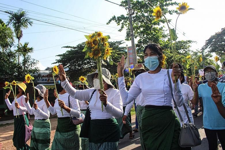 Protesters in Myanmar holding sunflowers during a demonstration on Wednesday against the Feb 1 military coup that has plunged the country into a political and economic crisis. PHOTO: AGENCE FRANCE-PRESSE