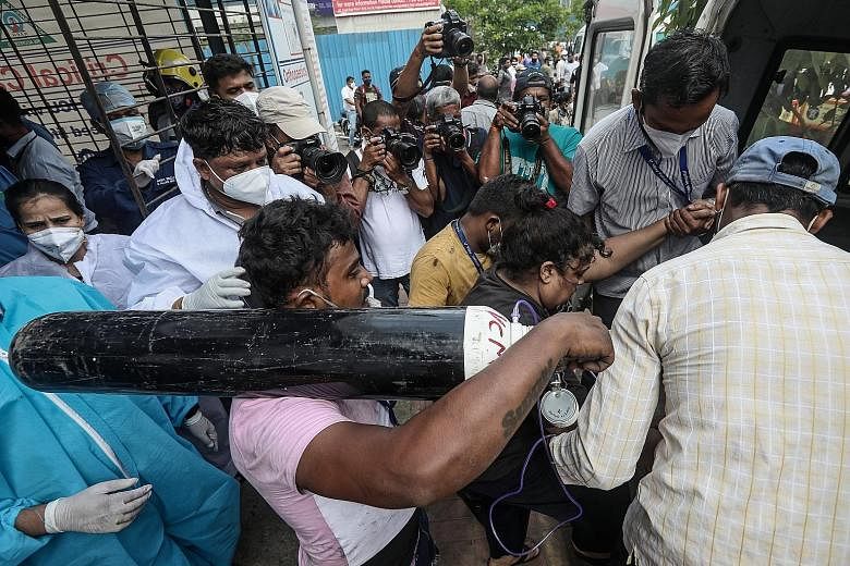 A man carrying an oxygen tank as health workers moved a suspected Covid-19 patient outside the Vijay Vallabh coronavirus care hospital in Virar West, on the outskirts of Mumbai, yesterday. A dire shortage of oxygen - essential for the survival of cri