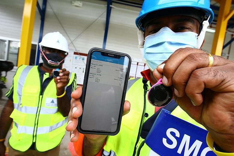 A safe management officer at a construction site showing a proximity device, which can detect workers' distance from one another. Technology has helped to make compliance with safety measures easier for many workers. PHOTO: LIANHE ZAOBAO