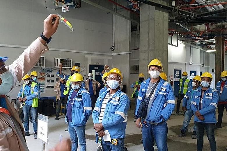 A Kajima construction site supervisor showing the TagBox contact tracing tag and briefing workers about it. The tag in a card holder exchanges Bluetooth signals with nearby tags to whom a worker was in close proximity with and it also emits a buzzing