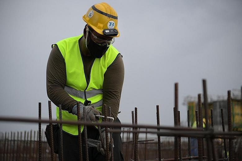 A worker with a TraceSafe contact tracing device on his safety helmet, at Boustead Singapore's construction site in Kranji in January. The Canadian firm is testing a smaller version of the device (above, right).