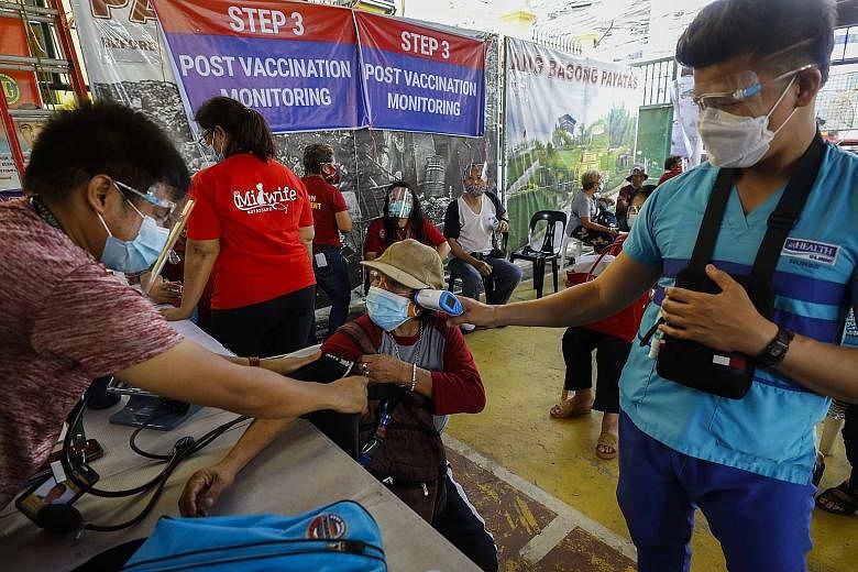 A Filipino undergoing post-vaccination monitoring after receiving a dose of the Sinovac vaccine yesterday in Quezon City, Metro Manila, where data crunchers said the number of Covid-19 cases is going down.