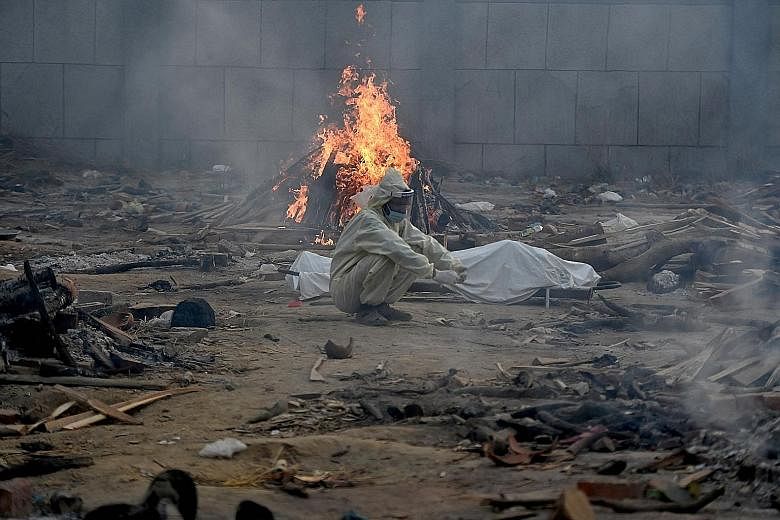A man sitting next to the body of a coronavirus victim, in front of the burning pyre of another victim at a cremation ground in Delhi on Monday. India is in the grip of a second Covid-19 wave. PHOTO: AGENCE FRANCE-PRESSE Oxygen tankers on a special t
