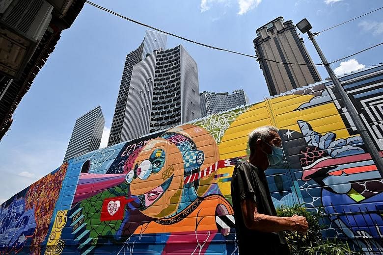 Above: Street artist Didier "Jaba" Mathieu adding the finishing touches to one of the murals along Bali Lane yesterday. Top and left: The 5m-high Graffiti Hall of Fame, a new Kampong Glam landmark, comprises stretches of street art that span nearly 2