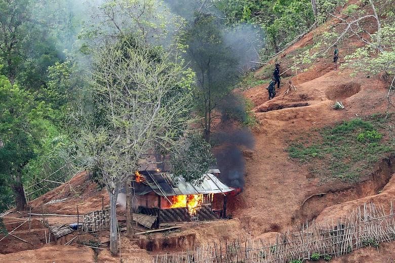 Ethnic minority Karen troops setting fire to a building inside a Myanmar army outpost near the Thai border on Wednesday. Recruits for a new force formed by protesters against Myanmar's military junta being taught ways to fight at a training camp in a