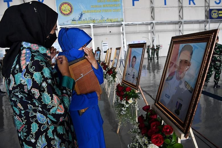 Relatives of a crew member of the sunken Indonesian submarine in front of his portrait during a posthumous promotion ceremony yesterday for all the 53 who perished last week. President Joko Widodo, who officiated at the ceremony in Sidoarjo, East Jav