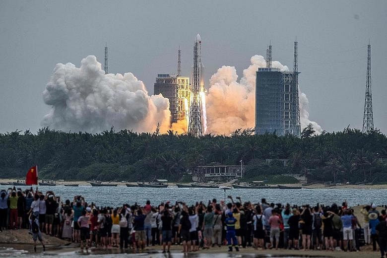 A crowd watching the lift-off of a Long March 5B rocket, carrying the Tiangong space station's core module, from Wenchang in Hainan province yesterday. China has invested billions of dollars in space exploration, with Beijing keen to showcase its ris