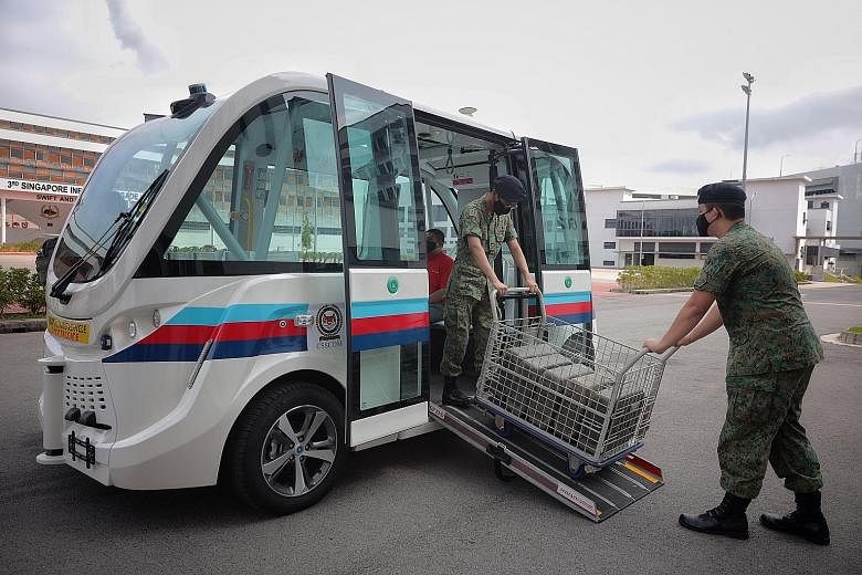 Servicemen loading jerry cans onto an autonomous vehicle in Kranji Camp III. A safety operator will be on board the vehicle - which has a maximum operating speed of 18kmh - at all times during the trial period. ST PHOTO: JASON QUAH