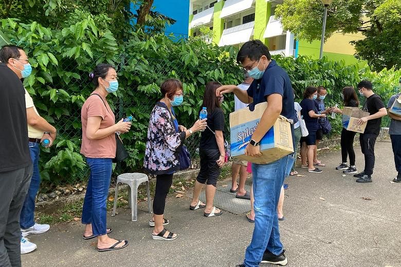 Bottled water being given to those queueing for Covid-19 tests at the former Da Qiao Primary School in Ang Mo Kio yesterday. By 11am, there were over 300 people in a line stretching 300m away from the facility.