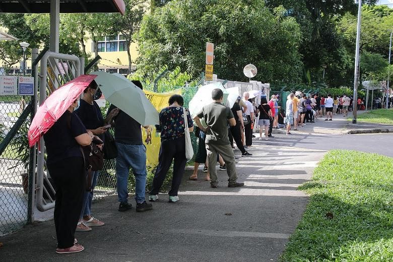 QUEUE AT REGIONAL SCREENING CENTRE: People queueing to get tested for Covid-19 yesterday at the former Da Qiao Primary School in Ang Mo Kio, one of four regional screening centres designated for free testing for people with possible exposure to the T