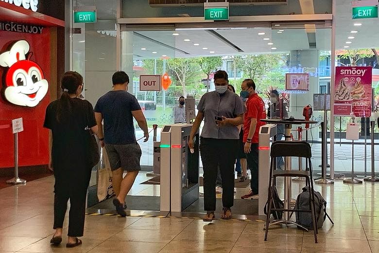 Visitors using the automated self-check-in gantry system at Square 2 shopping mall in Novena yesterday. The system ensures they check in with SafeEntry, and the gantry has cameras that measure body temperature.