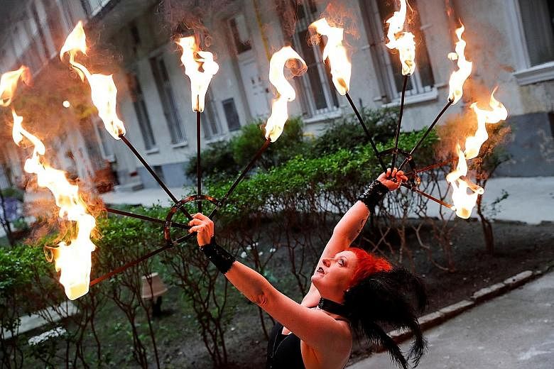 Hungarian circus artiste Eszter Kovacs, a member of the Taurin Circus Group, practising fire-juggling in the courtyard of her apartment block in Budapest, last week.