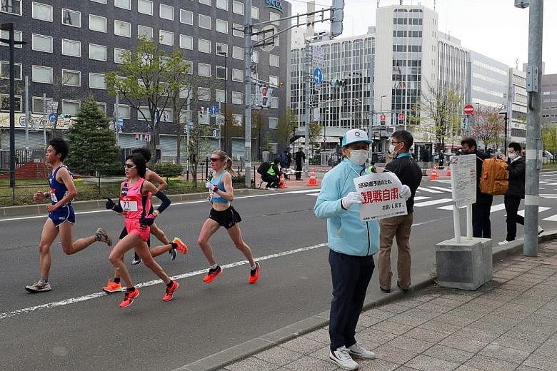 A volunteer holding a sign asking people to refrain from watching a half-marathon in Sapporo on Thursday. It was a test event for the Games.