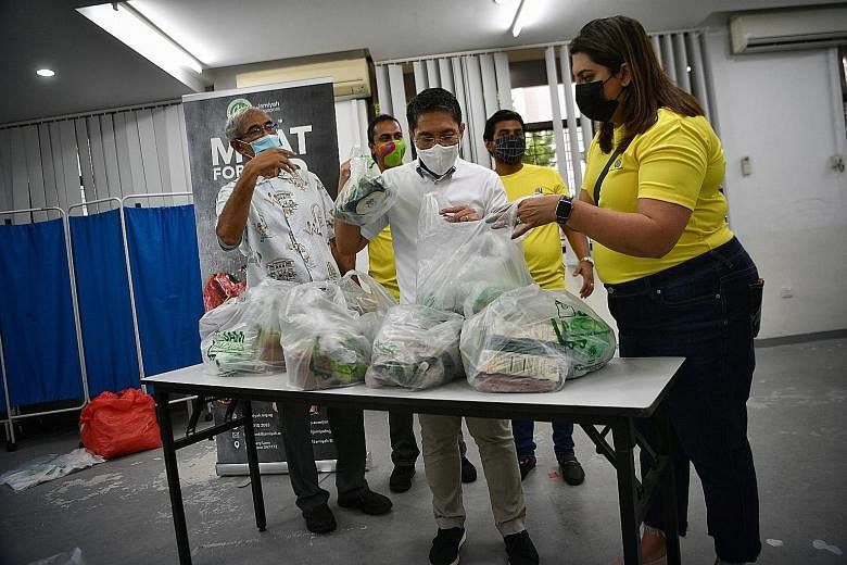 Minister in the Prime Minister's Office Maliki Osman (centre) helping to pack festive gift packs at the Siglap Community Centre on Saturday. Each contains 2kg of meat, two chickens, basmati rice, rendang paste and a packet of instant ketupat, so fami