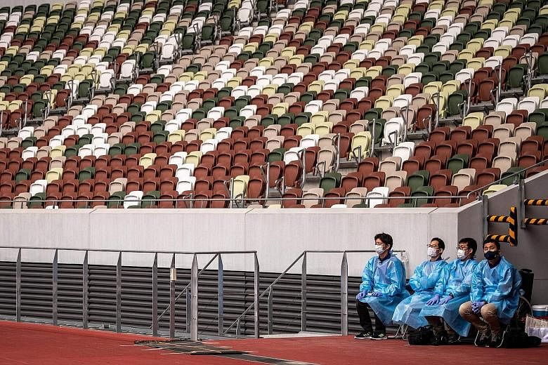 Staff in protective gear during a test event for the Tokyo Olympics at the National Stadium in Tokyo this week. The 78,000 volunteers for the Games are reportedly being allotted a handful of cloth masks, some sanitiser and social-distancing slogans, 