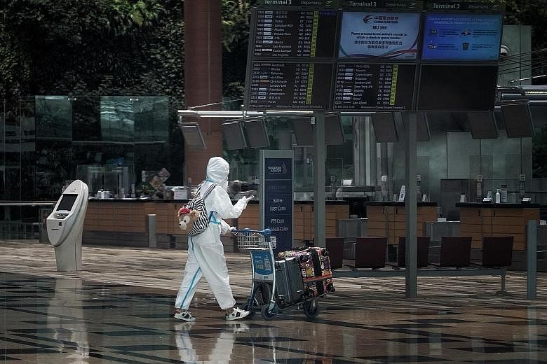 An airline passenger wearing personal protective gear at Changi Airport Terminal 3 yesterday. Only some workers and travellers are allowed to access the airport terminal buildings for two weeks from yesterday. The closure comes as the authorities emb