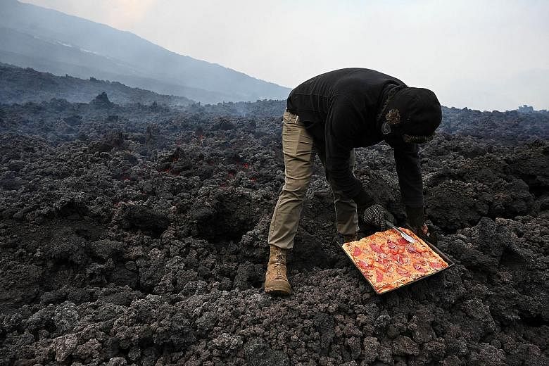 Mr David Garcia cooking a pizza on smouldering volcanic rock from the Pacaya volcano in Guatemala on Tuesday. "Many people today come to enjoy the experience of eating pizza made on volcanic heat," said the accountant, whose "kitchen" has become a ma