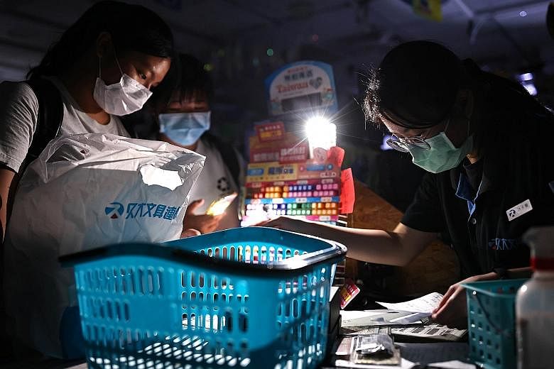 People using a mobile phone for light as they paid for their purchases in a store during a blackout in Taipei on Thursday. Taipower said engineers had been carrying out tests at a substation as part of a power plant expansion project in the city of K