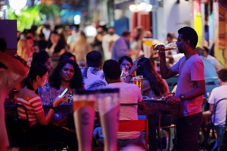Revellers in Haji Lane yesterday. Starting from today until June 13, gatherings are capped at two people and dining in is prohibited. Hawker stall operators said the tightened measures would cause a slump in business, but those who are tenants of gov