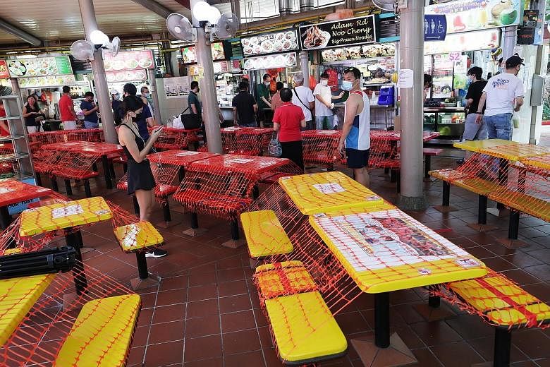 Customers queueing for food at Adam Road Food Centre yesterday, the first day of stricter Covid-19 measures which will last till June 13. As part of the new rules, dining in is not allowed, and eateries and hawker centres will offer only takeaway and