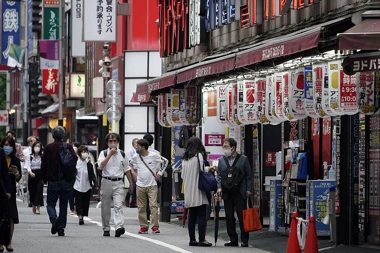 Pedestrians in Tokyo's Shinjuku business and entertainment district yesterday. The contraction of Japan's economy in the first quarter ended six months of double-digit growth, as businesses cut investment, shoppers held back spending and government o