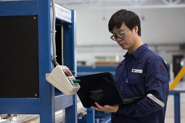 A quality technician extracting data from an automated optical camera system at the Tuas premises of manufacturer Completion Products. An ICF International employee testing virtual reality tools. The company, which provides solutions for the marine a