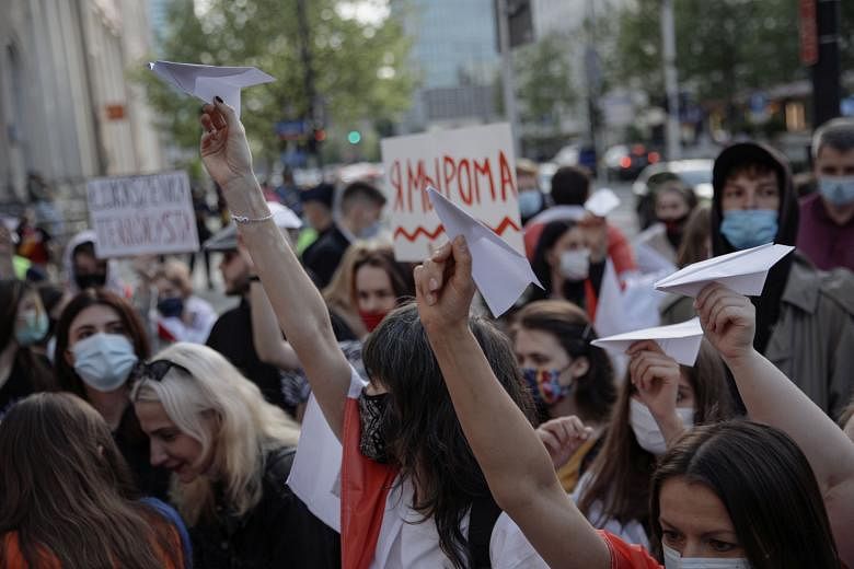 People holding paper planes on Monday during a protest in Warsaw, Poland, against the detention of Belarusian blogger Roman Protasevich, who was detained as a Ryanair plane that he was on en route from Athens to Vilnius was forced to land in Minsk.