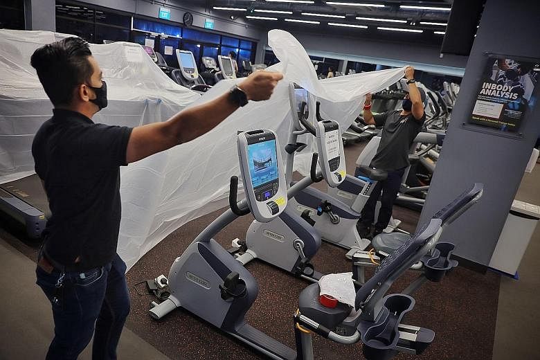 Staff covering up treadmills in the True Fitness gym at HarbourFront Centre on May 7, the last day before tighter measures kicked in. Eligible gyms and fitness studios can tap 50 per cent wage support under the Jobs Support Scheme from May 16 to June